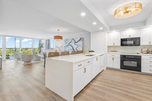 kitchen featuring white cabinets, hanging light fixtures, sink, black appliances, and kitchen peninsula