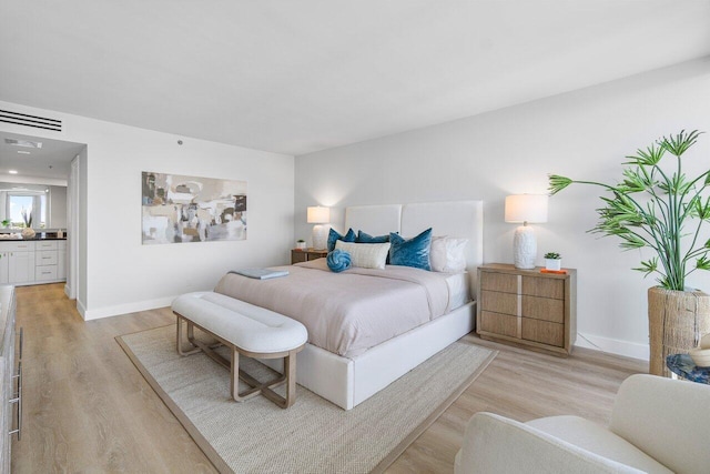 bedroom with light hardwood / wood-style flooring and connected bathroom