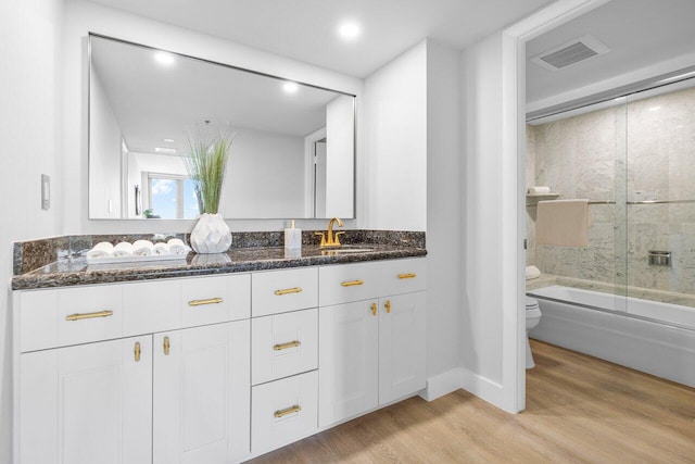 full bathroom with enclosed tub / shower combo, toilet, wood-type flooring, and vanity