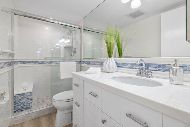 bathroom with an enclosed shower, toilet, wood-type flooring, tasteful backsplash, and vanity