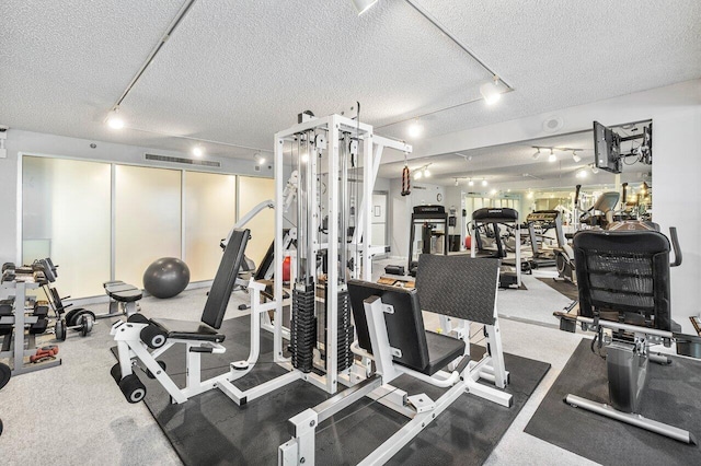 gym featuring track lighting and a textured ceiling