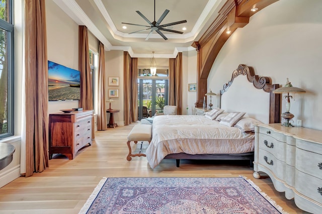 bedroom with light wood-type flooring, ornamental molding, and a tray ceiling