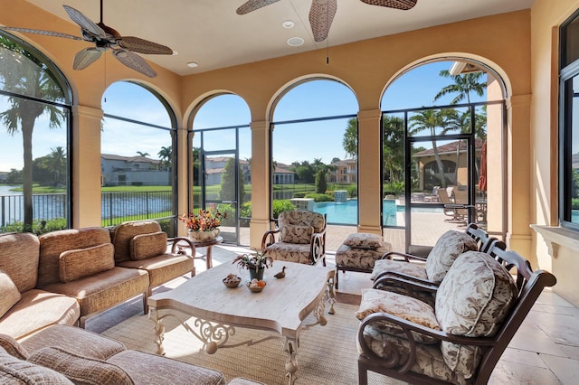 sunroom with a wealth of natural light, a water view, and ceiling fan