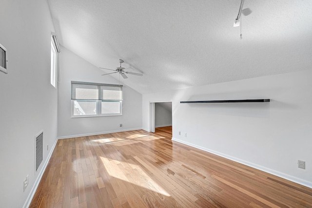 unfurnished living room featuring lofted ceiling, hardwood / wood-style floors, ceiling fan, and a textured ceiling