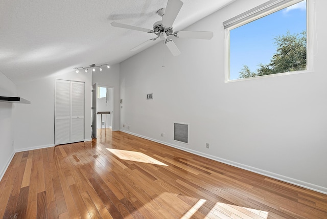 unfurnished living room featuring a textured ceiling, ceiling fan, light wood-type flooring, and lofted ceiling