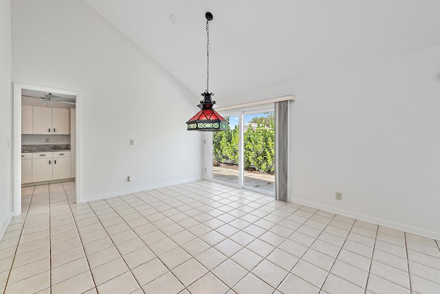 empty room featuring lofted ceiling, ceiling fan, light tile patterned floors, and a textured ceiling