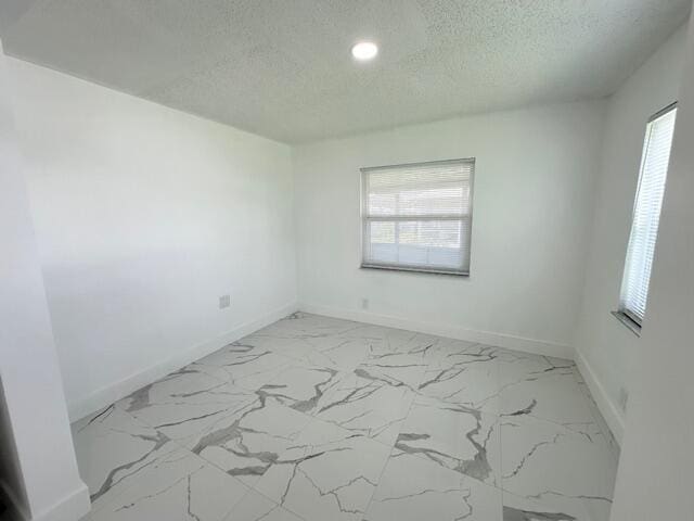 unfurnished room with a textured ceiling