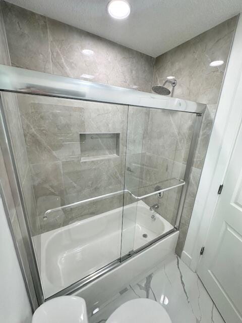 bathroom with toilet and bath / shower combo with glass door