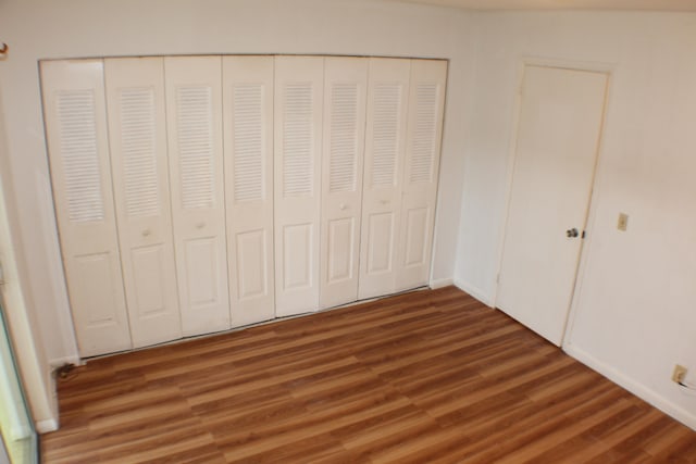 unfurnished bedroom with a closet and dark hardwood / wood-style flooring