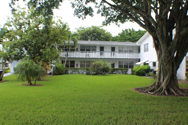 view of front of home with a balcony and a front yard