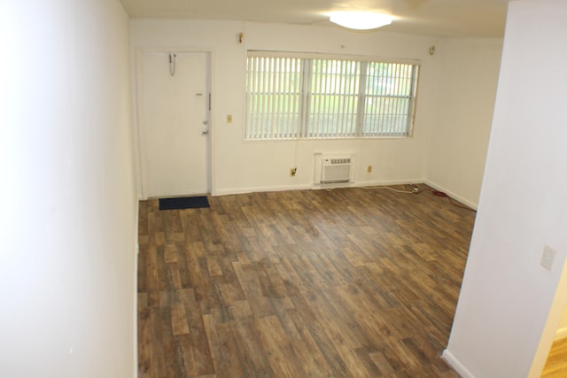 spare room with a wall unit AC and dark hardwood / wood-style flooring