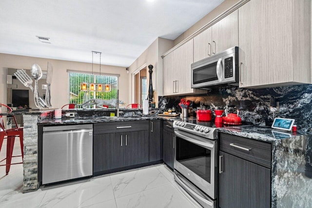 kitchen featuring visible vents, appliances with stainless steel finishes, tasteful backsplash, a peninsula, and dark stone countertops