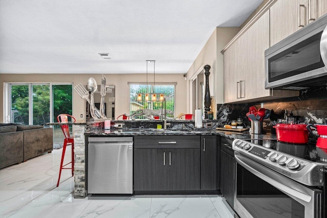 kitchen with an inviting chandelier, plenty of natural light, stainless steel appliances, open floor plan, and a peninsula
