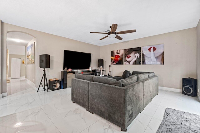 living room with arched walkways, baseboards, a ceiling fan, and marble finish floor