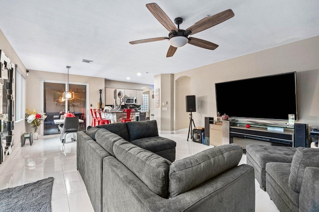living area with arched walkways, a ceiling fan, marble finish floor, and visible vents
