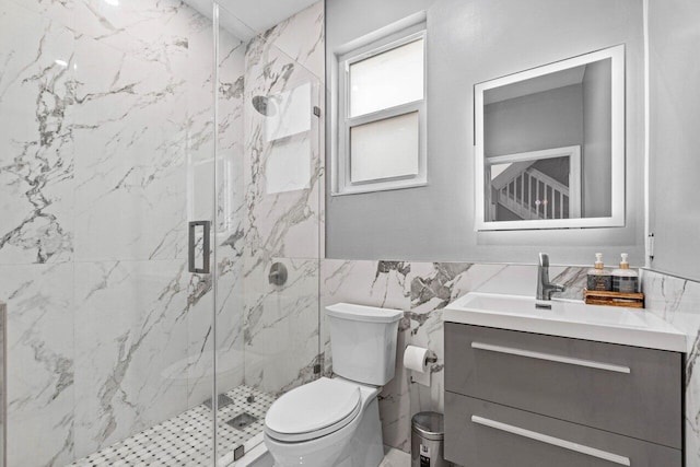full bath with a marble finish shower, vanity, toilet, and tile walls