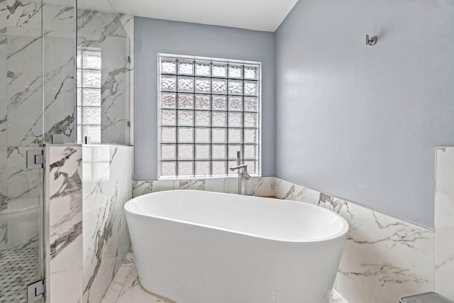 full bathroom with a freestanding bath, wainscoting, a marble finish shower, marble finish floor, and tile walls