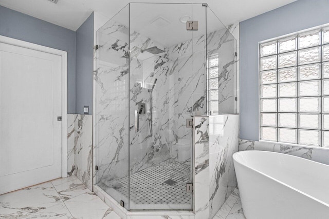 full bathroom featuring marble finish floor, a marble finish shower, and a soaking tub