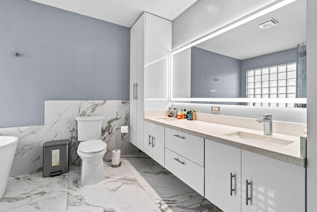 bathroom with double vanity, wainscoting, marble finish floor, toilet, and a sink