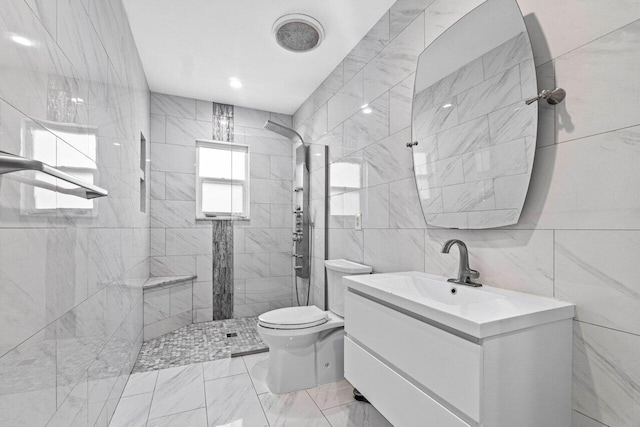 full bath featuring vanity, marble finish floor, toilet, tile walls, and tiled shower