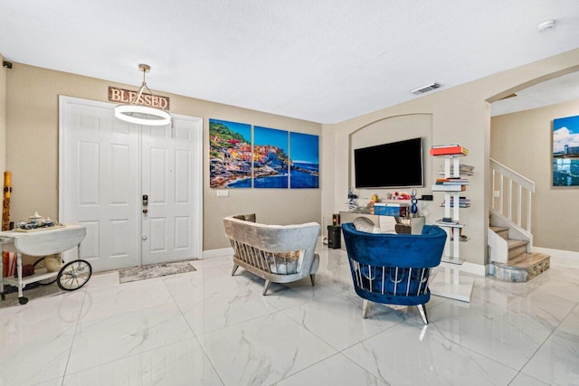 living room featuring baseboards, marble finish floor, and stairs