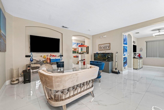 living area with arched walkways, baseboards, visible vents, and marble finish floor