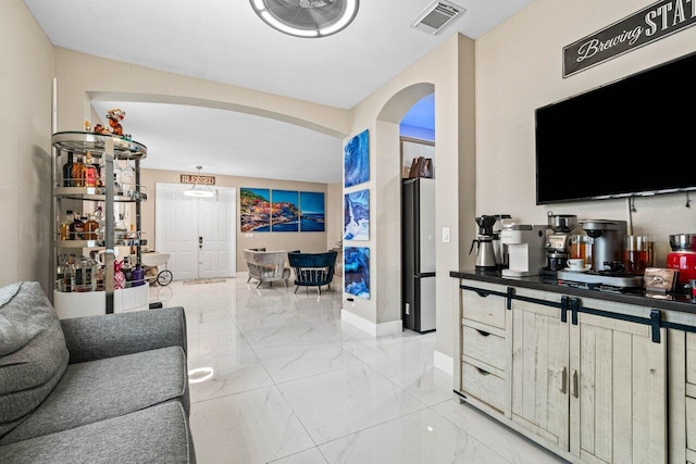 living area with visible vents, arched walkways, marble finish floor, and baseboards