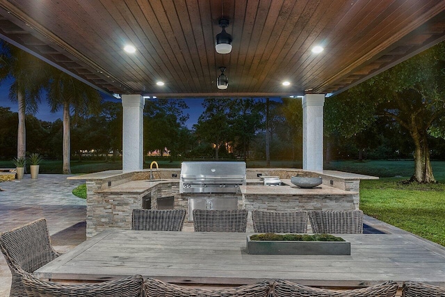 patio at twilight with grilling area, area for grilling, a yard, and sink