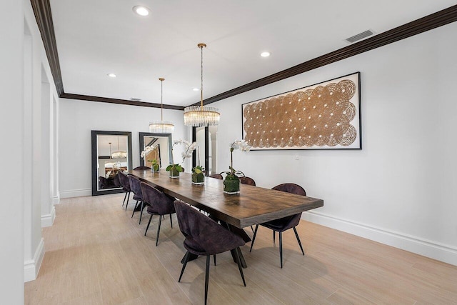 dining room featuring light hardwood / wood-style flooring, crown molding, and a chandelier