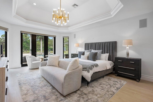 bedroom with light hardwood / wood-style floors, a tray ceiling, and a notable chandelier