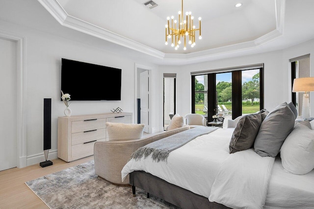 bedroom featuring ornamental molding, light wood-type flooring, a chandelier, and a raised ceiling