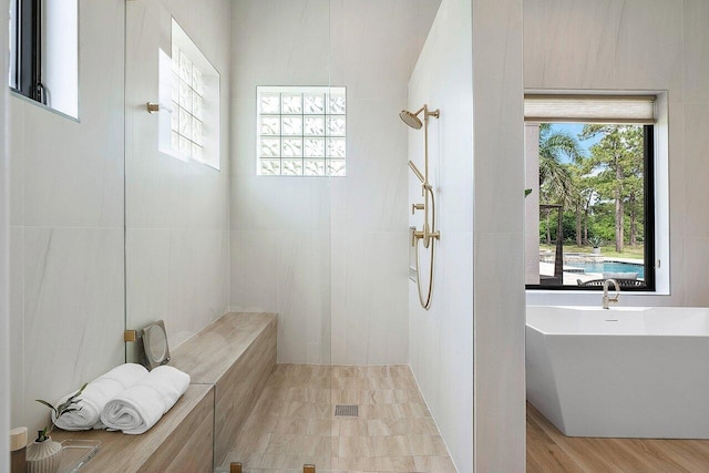 bathroom with a tub to relax in and hardwood / wood-style flooring