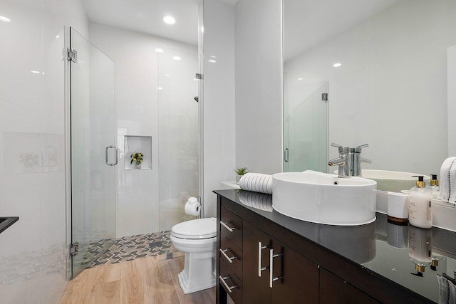 bathroom featuring vanity, toilet, a shower with shower door, and hardwood / wood-style floors