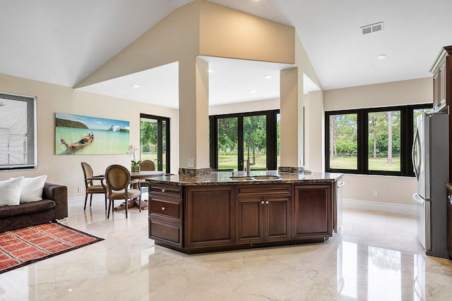 kitchen featuring dark stone counters, lofted ceiling, dark brown cabinetry, and sink