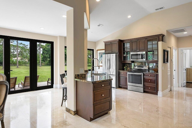 kitchen featuring dark stone counters, dark brown cabinets, sink, vaulted ceiling, and stainless steel appliances