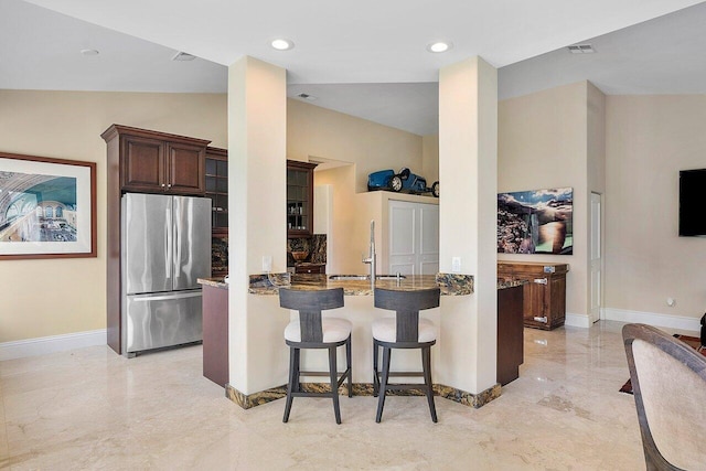 kitchen with sink, kitchen peninsula, dark brown cabinets, stainless steel refrigerator, and a breakfast bar area