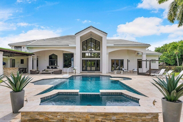 rear view of property with a patio, french doors, and a pool with hot tub