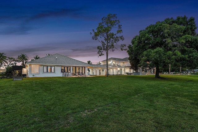 back house at dusk featuring a yard