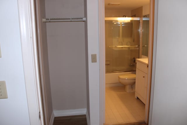 full bathroom featuring combined bath / shower with glass door, vanity, and toilet