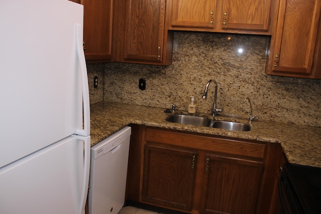 kitchen with white appliances, stone counters, sink, and tasteful backsplash