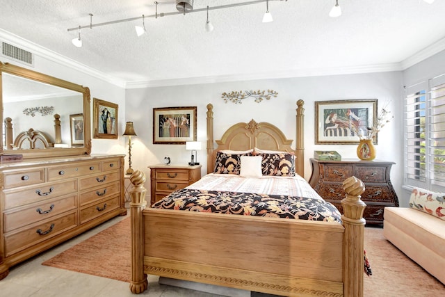 bedroom with rail lighting, ornamental molding, and a textured ceiling