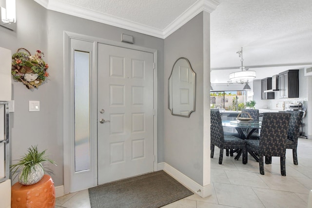 foyer entrance with light tile patterned floors, ornamental molding, and a textured ceiling