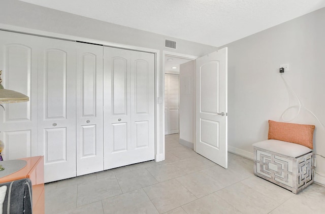 tiled bedroom with a textured ceiling and a closet