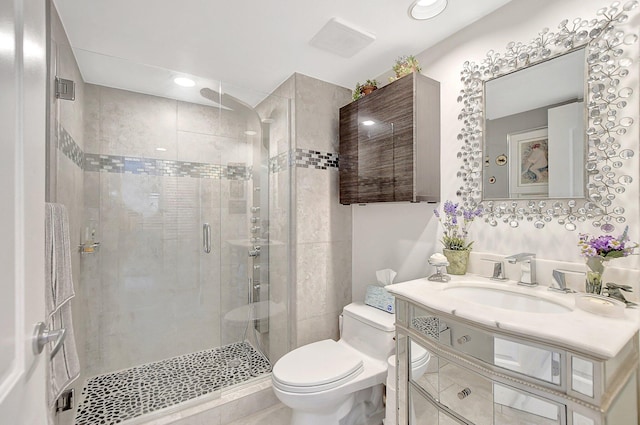 bathroom with a shower with door, vanity, and toilet