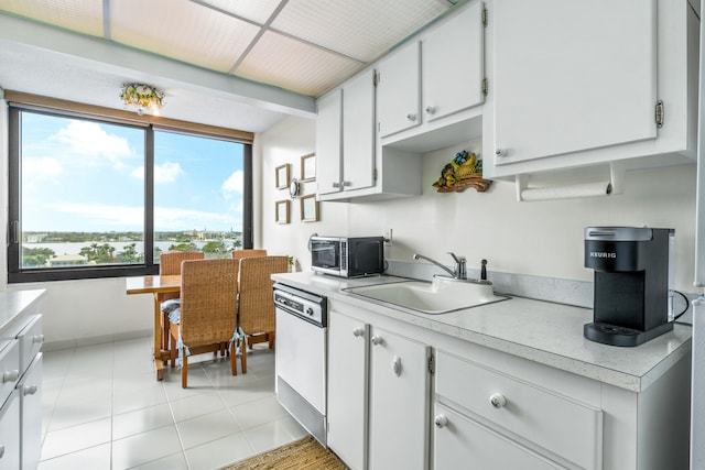 kitchen with light tile patterned flooring, sink, white dishwasher, and white cabinets