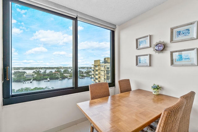 dining room featuring a water view and a textured ceiling