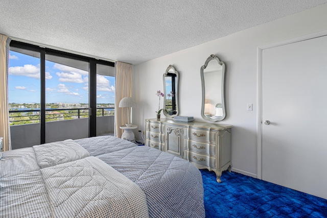 bedroom featuring a textured ceiling, access to outside, dark colored carpet, and expansive windows