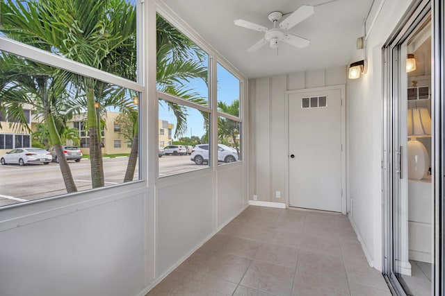 unfurnished sunroom with ceiling fan