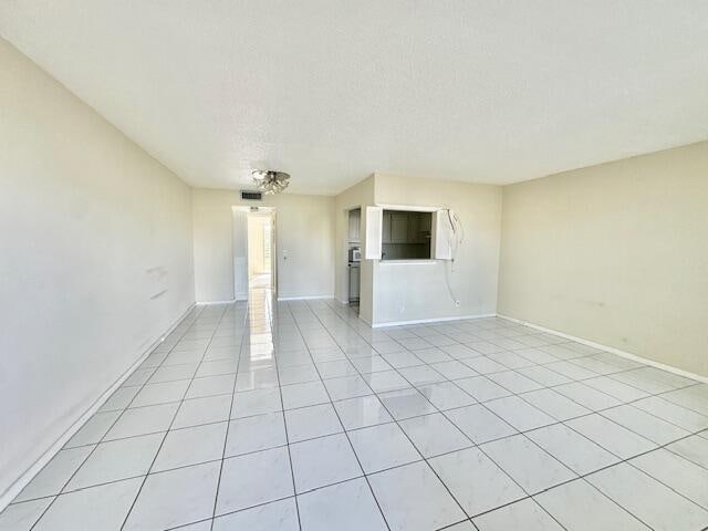 unfurnished living room featuring light tile patterned floors and a textured ceiling