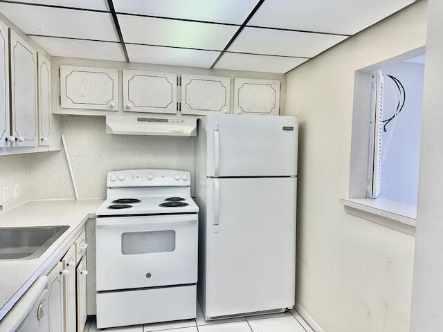 kitchen with range hood, white cabinets, white appliances, sink, and a drop ceiling